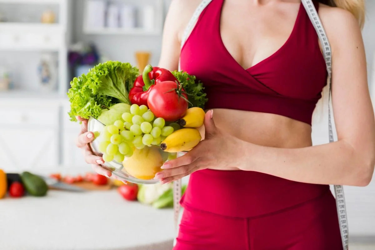 kobieta trzyma w rękach miskę z warzywami i owocami