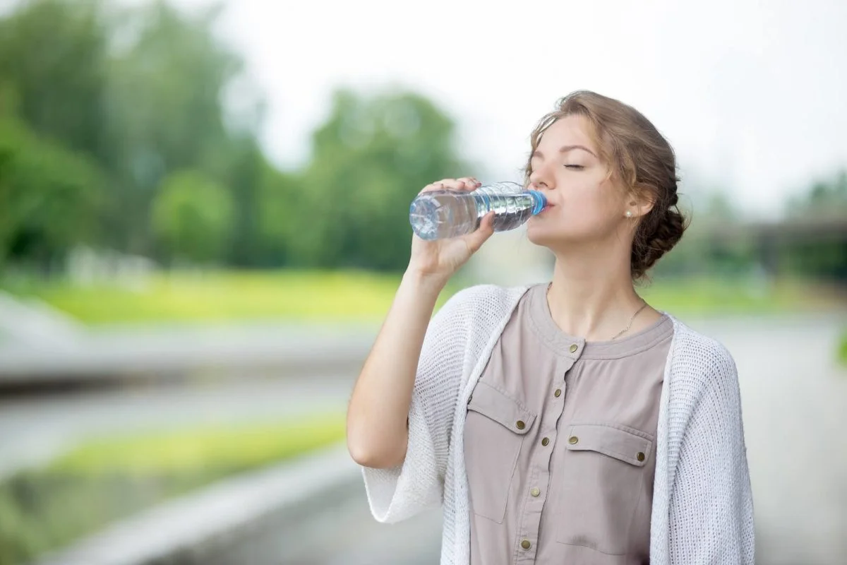 kobieta pije wodę z butelki po posiłku ze swojego cateringu codziennego