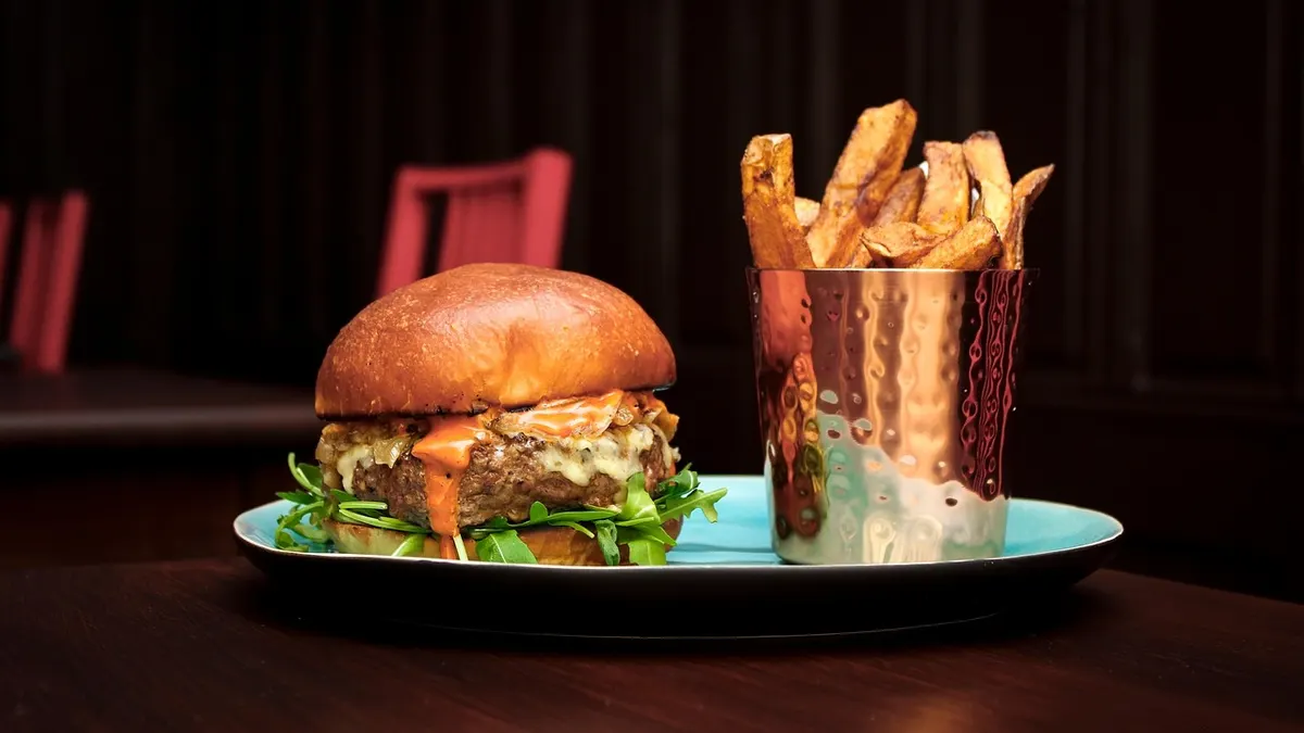 Burger z serem i frytkami na tacy w restauracji fast food