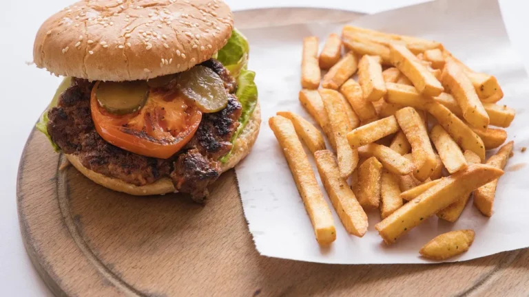 Burger z serem, frytkami i napojem na tacy w restauracji szybkiej obsługi