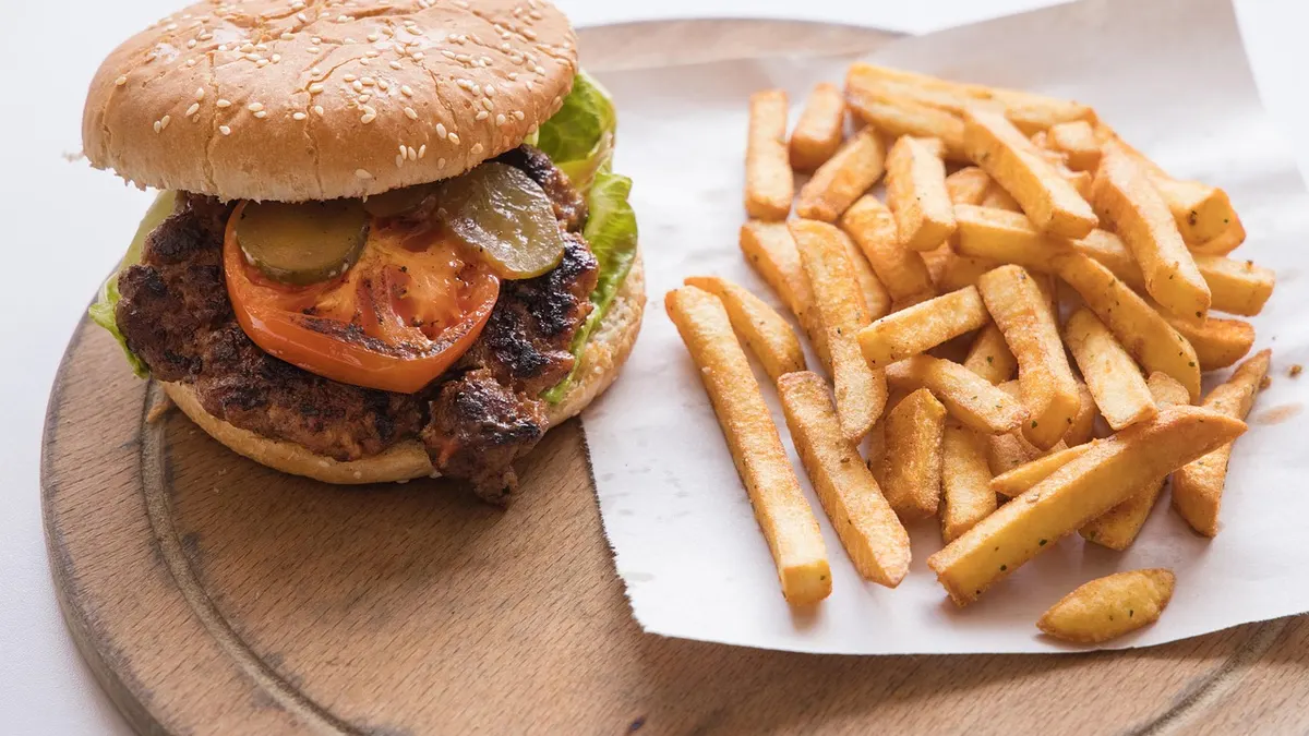 Burger z serem, frytkami i napojem na tacy w restauracji szybkiej obsługi
