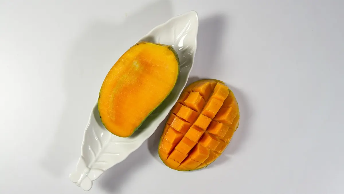 Pokrojone dojrzałe mango na desce obok całego owocu
