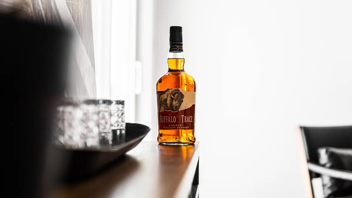Szklanka whisky z kostkami lodu obok butelki alkoholu