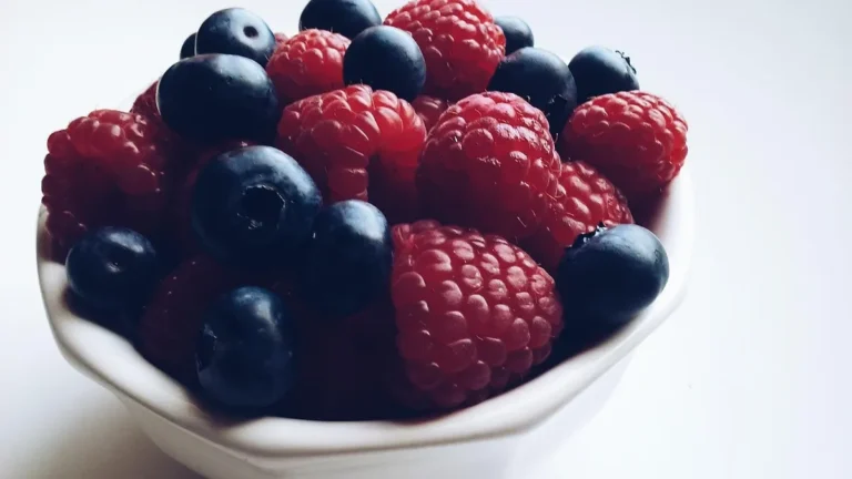 Świeże borówki amerykańskie w misce obok miarki kuchennej