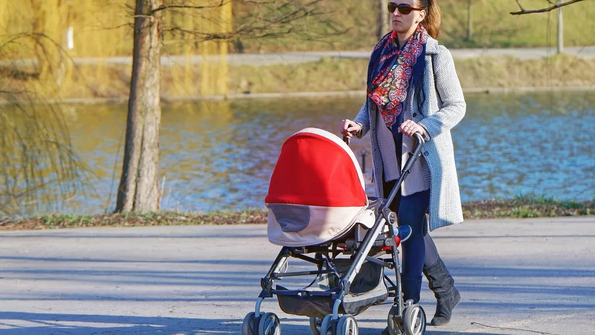 Mama spacerująca z wózkiem po parku jako łagodna aktywność po ciąży