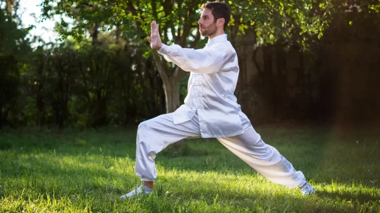 Osoba ćwicząca tai chi w parku, wykonująca łagodne ruchy wspierające kręgosłup