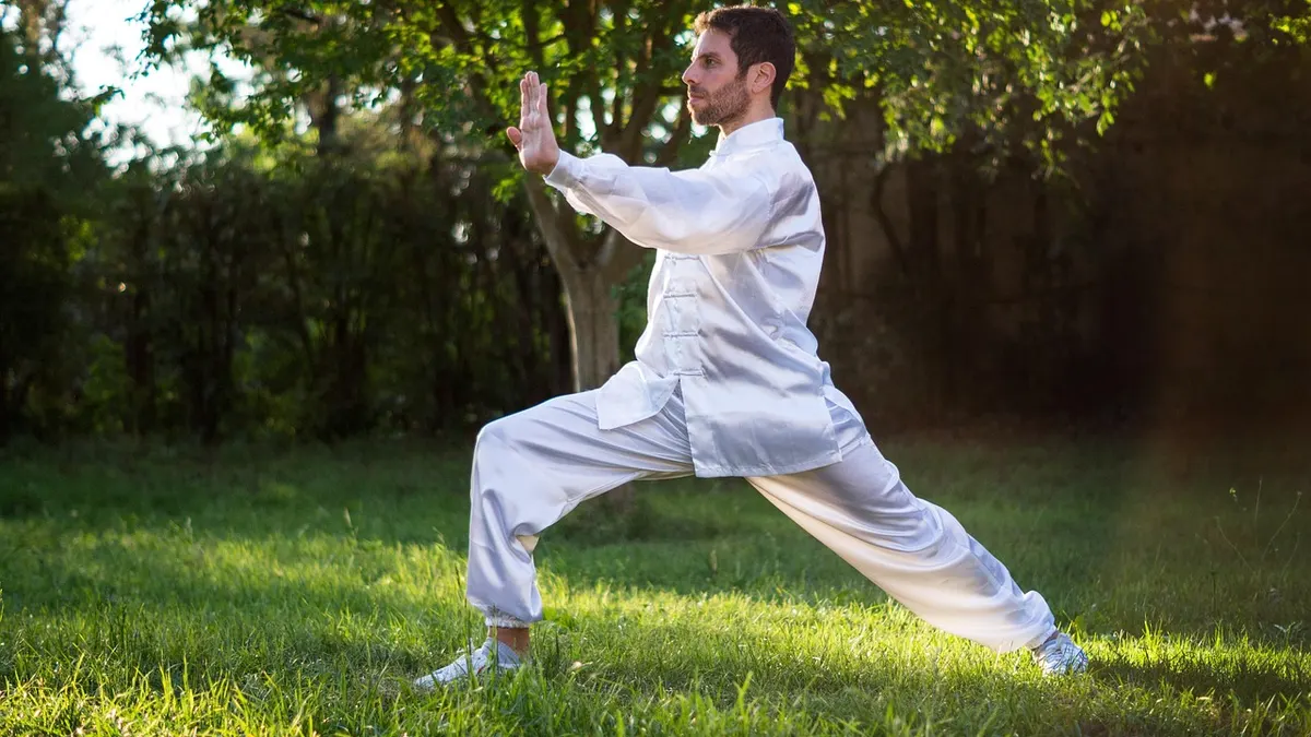 Osoba ćwicząca tai chi w parku, wykonująca łagodne ruchy wspierające kręgosłup